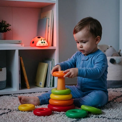 Enfant joue sous la lumière de sa veilleuse bébé coccinelle