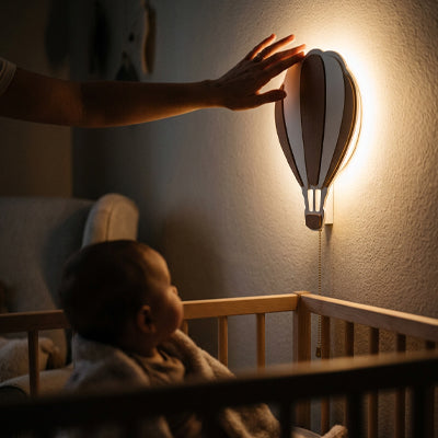 bébé regarde sa veilleuse murale montgolfière