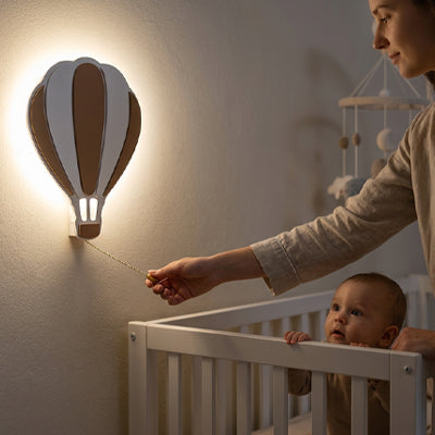 maman allume veilleuse murale montgolfière devant bébé